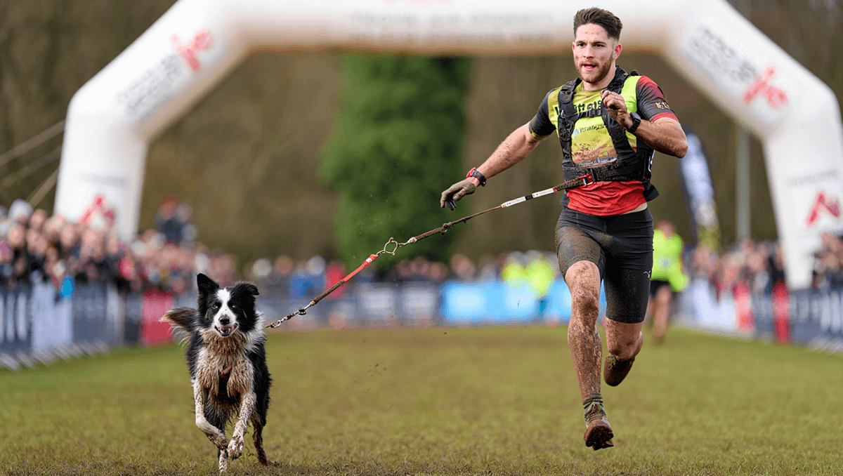 Спортсмен и его собака финишируют на соревнованиях по каникроссу